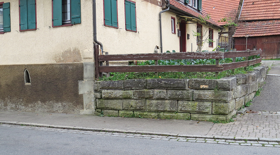 Abb. 3: Kappelstraße 9 mit Vorgarten im Buckelquadergeviert. Links unten ist das  vermutlich zur  abgegangenen Kapelle gehörige frühgotische Fenster zu erkennen, das mit der Innenseite nach außen in den Keller eingebaut wurde.