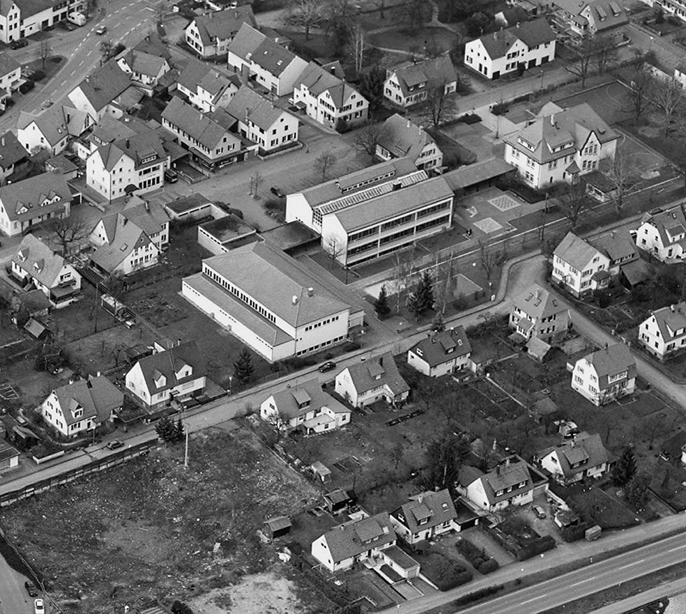 Abb. 4: Luftaufnahme mit Blick über das Schulgelände im Jahr 1997. Rechts oben das alte Schulhaus von 1908. Die überdachte Pausenhalle verbindet es mit dem neuen Schulhaus in der Bildmitte. Quer dazu steht die Turn- und Festhalle.